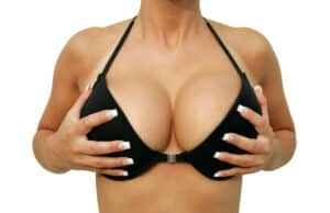 closeup of a woman in bikini is holding her made breasts, isolated.