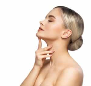 Woman looking up and holding her neck to show off her profile after a neck lift