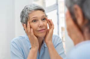 A woman looking in the mirror considering eyelid surgery in Miami