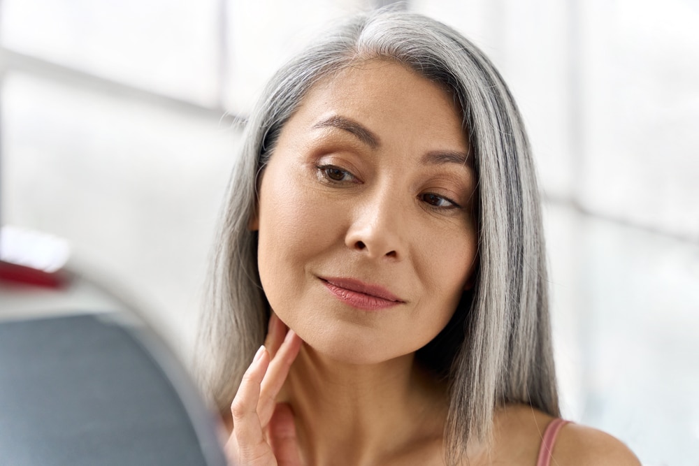 A woman looking in the mirror after neck liposuction in Miami A woman looking in the mirror after neck liposuction in Miami FL