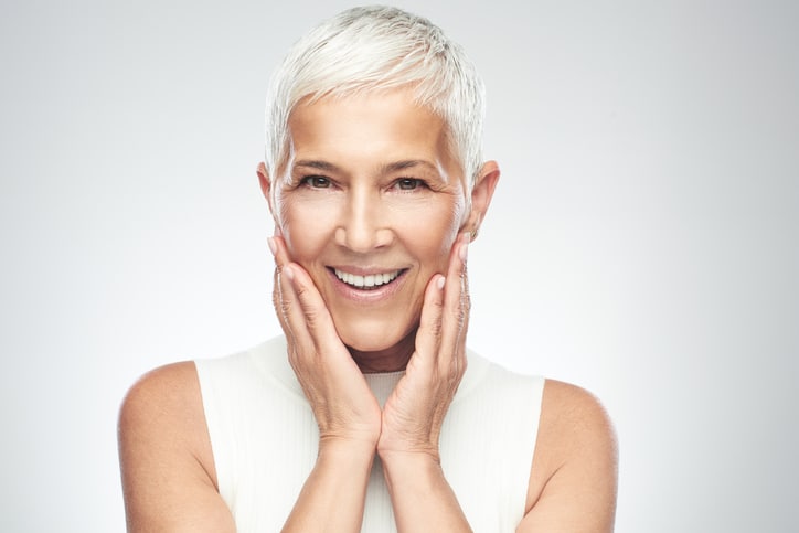 A mature woman touching her cheeks after a facelift in Miami