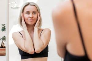 A woman looking in the mirror after a facelift in Miami, FL