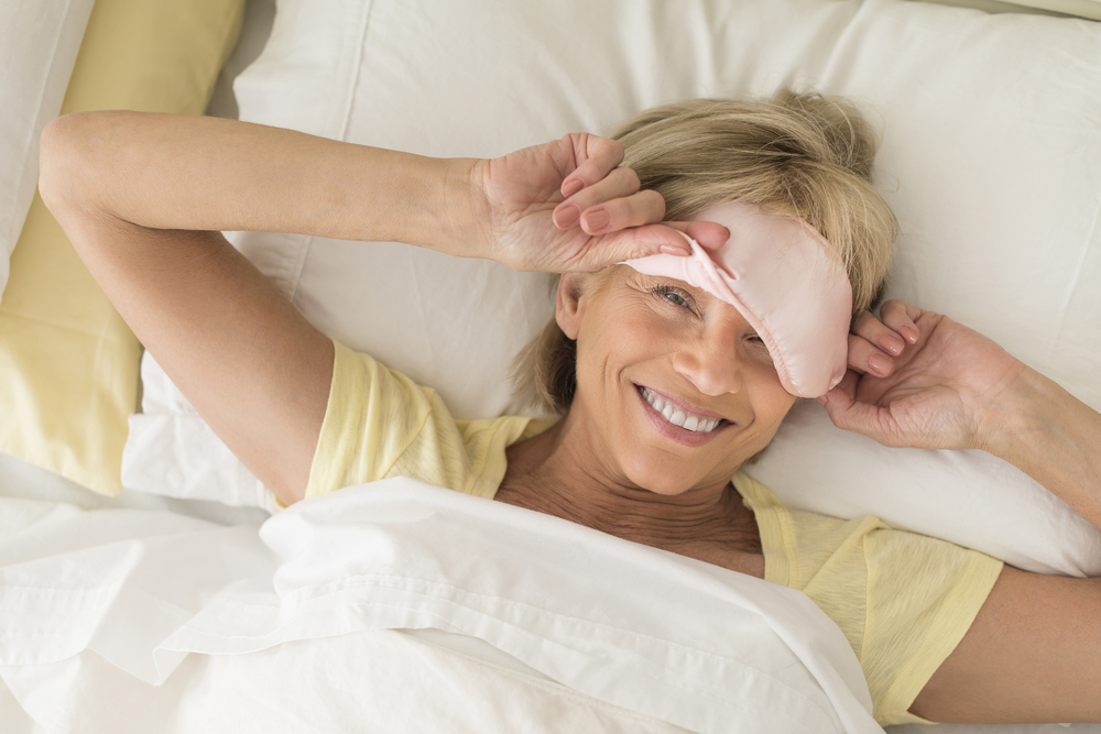 Woman taking off sleep mask smiling after ear pinning surgery in Miami