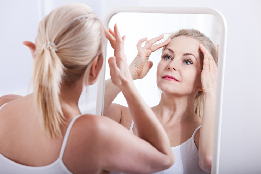 Woman looking in the mirror at swelling after a facelift in Miami